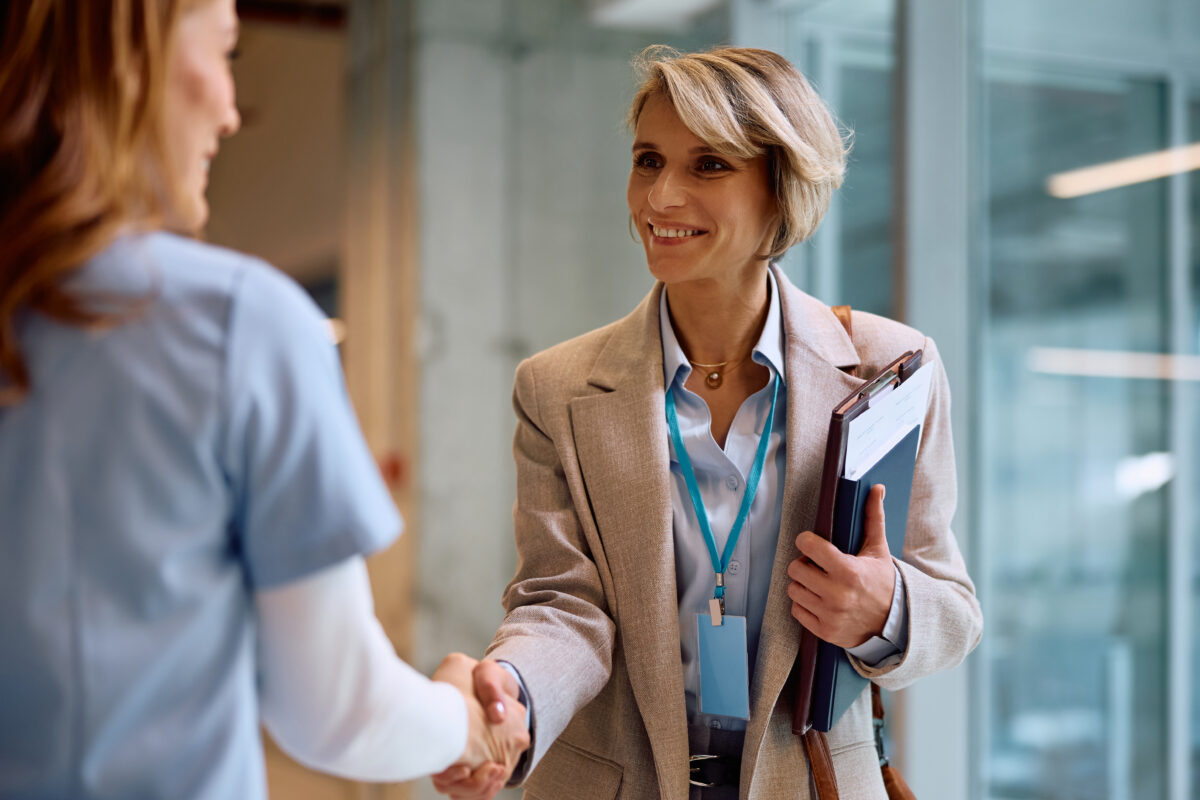 Happy businesswoman greeting a nurse while meeting in a hospital.